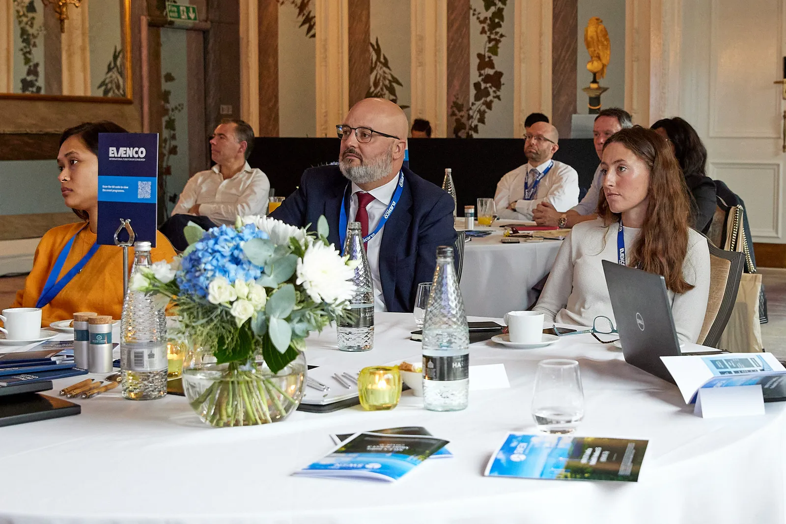 Delegates seated at round tables during a conference session